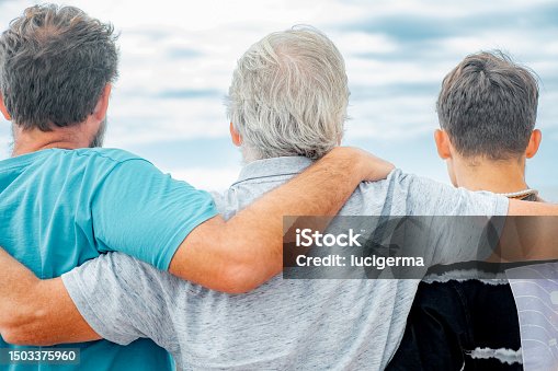 istock Rear view of family multi generation, father, teenage son and grandfather hugging with love. Handsome people relaxing together 1503375960