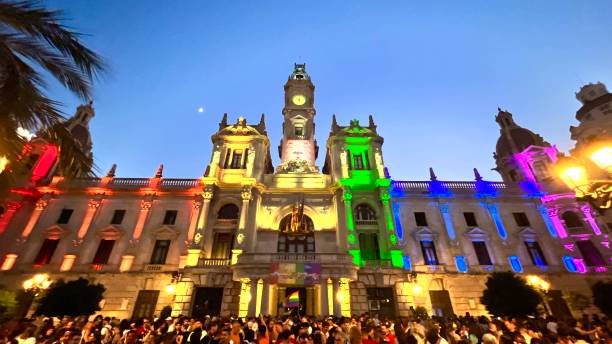 Valencia, Comunidad Valenciana, Spain - June 24, 2023: Participants wave flags and hold banners as they gather in front of the Valencia's Municipal Government Building during the Valencia's Gay LGBTI Pride.