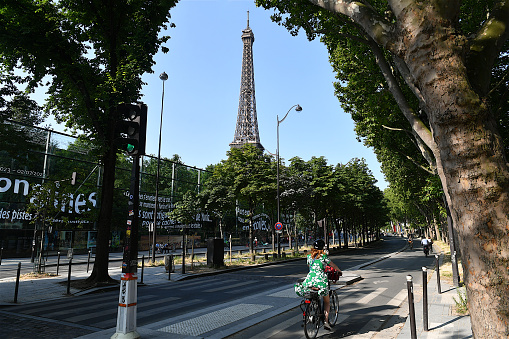 Paris, France-06 28 2023: People riding bicycle in a street of Paris, with the Eiffel tower in the background, France.