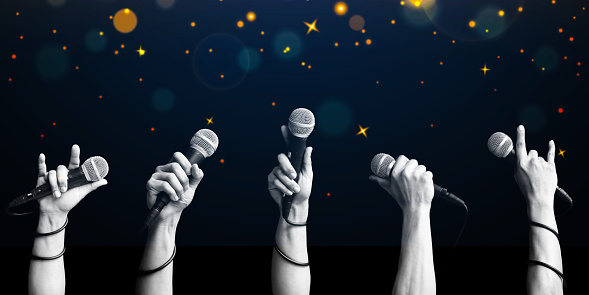 microphone in hands on twinkling stars background. singing contest concept