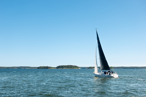 Regatta sailing ship yachts with white sails at opened sea. Aerial view of sailboat in windy condition.