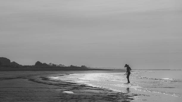 istock a model walking in an empty beach in summer with a hat at sunset, monochrome shot. 1503384341