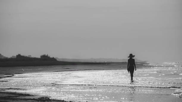 istock a model walking in an empty beach in summer with a hat at sunset, monochrome shot. 1503384342