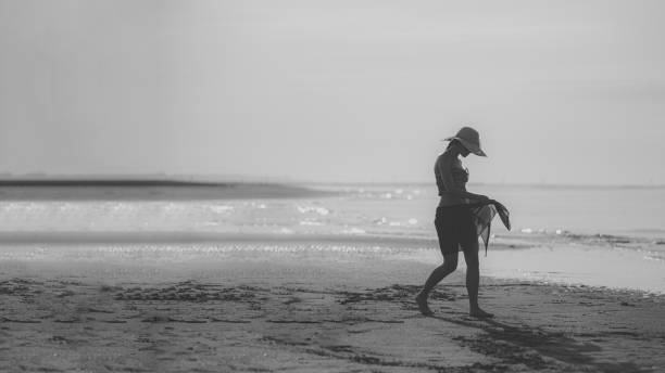 istock a model walking in an empty beach in summer with a hat at sunset, monochrome shot. 1503384347