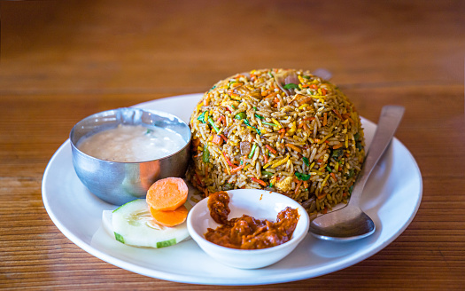 Fried rice with chicken and vegetables in white plate on wooden table