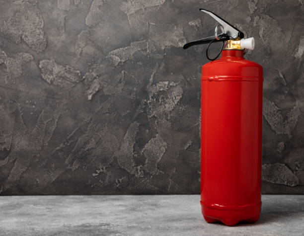 istock Fire extinguisher on the background of a black texture wall. Red fire extinguisher indoors on the wall. Fire protection, home fire extinguisher. Mockup, space for text, copy space. 1503389230