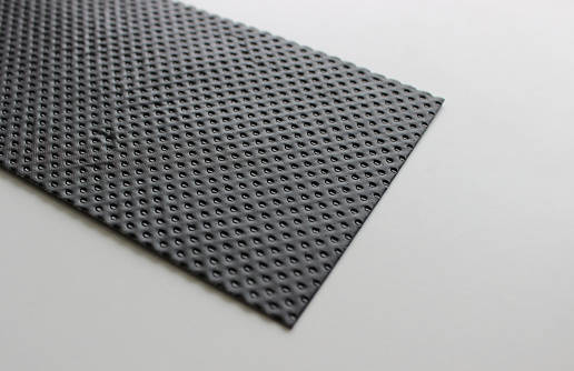 Part Of Black Perforated Panel On White Surface Angle View