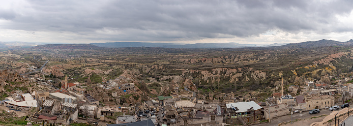Uchisar, Turkey - April 13, 2023: A panorama picture of the Goreme Historical National Park, and the town of Uchisar, on a cloudy day.