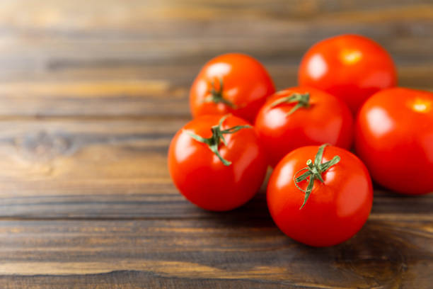 Fresh red tomatoes on  texture background. Cherry tomatoes with green stems.Fresh vegetables. Place to copy.