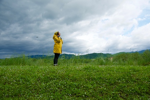 Girl look at cloudy sky weather in profile with yellow raincoat
