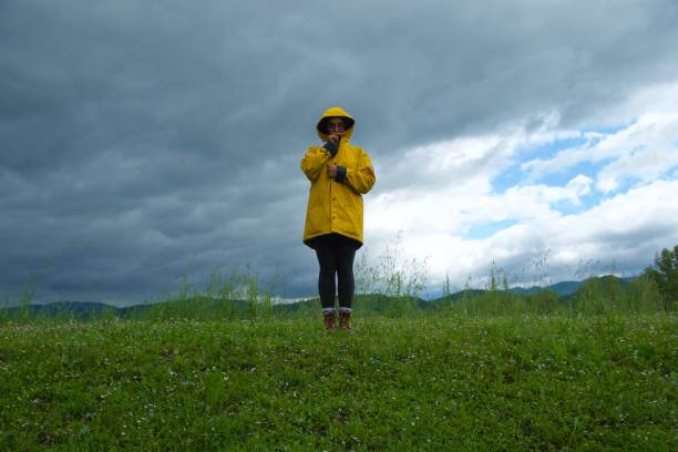 Girl looking at camera with cloudy sky weather with yellow raincoat