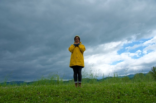 Girl look at camera with cloudy sky weather wearing  yellow raincoat