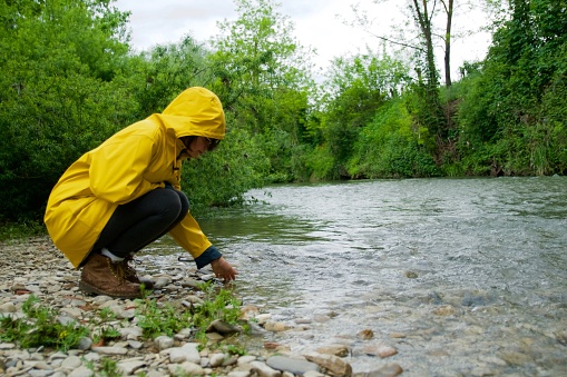 Girl on river side with yellow raincoat, enjoy nature in a rainy day concept