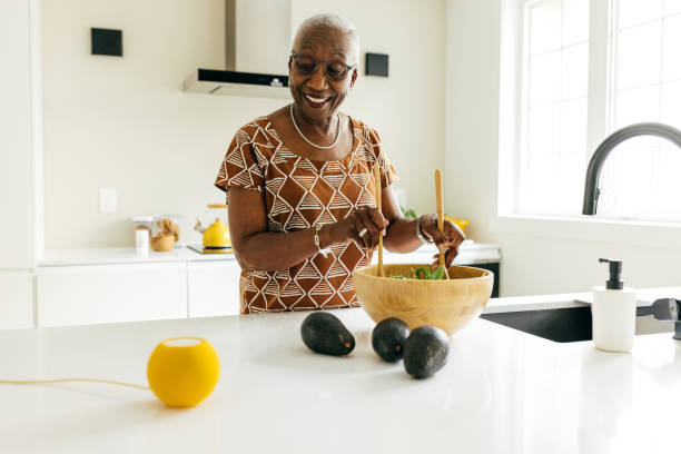 istock Senior women talking to virtual assistant on her kitchen while mixing salad 1503398413