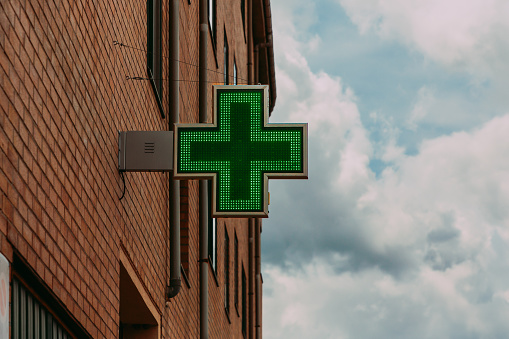 Green pharmacy sign on the brick facade of the building