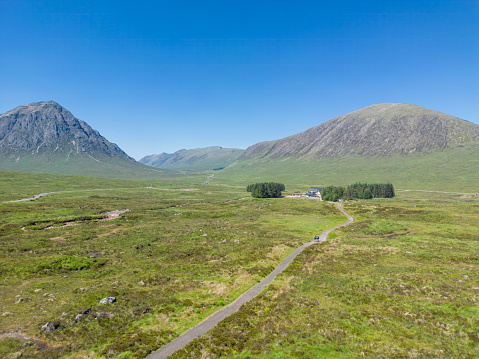 Drone view of West Highland Way trail in the Scottish highlands with hikers on trail headed toward mountain.