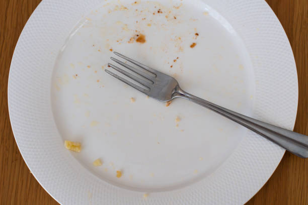 istock Empty dirty witw plate and fork on wooden table. Closeup top view . 1503406234