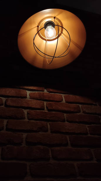 istock A black iron modern lamp shines on a brick wall. Red brick wall and ceiling lamp 1503414194