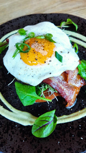 istock Breakfast. Classical American dinner or French Bistro brunch item favorite. Breakfast of scrambled eggs and bacon, garnished with herbs, served on a black plate 1503414904