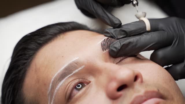 Close up shot of male microblading procedure to making permanent eyebrows makeup