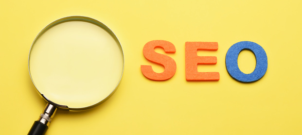 SEO concept. Search engine optimization. A magnifying glass and word seo on the yellow background