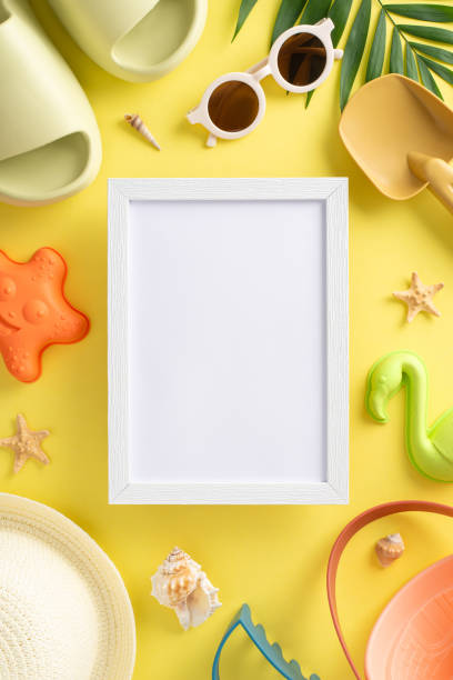 istock Fun activities for child on vacation concept. Top vertical view photo of empty frame with slippers, panama and sunglasses, beach child toys, palm leaf and shells on yellow isolated background with copy-space 1503434356