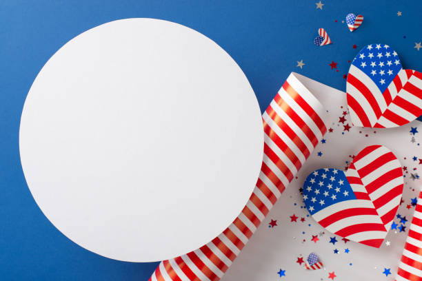 istock Preparations underway for USA's Independence Day. Top view patriotic-themed wrapping paper, heart-shaped designs with American flag. Confetti create captivating scene on blue backdrop, circle for text 1503437921