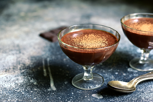 Chocolate mousse with nuts in a glasses on a slate, stone or concrete table.