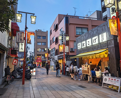 May 27, 2023 - Taito Ward, Japan: Outdoor diners and pedestrians spend a weekend evening on Kannondori Street in the Asakusa entertainment district. Looking north on Kannondori Street in springtime.