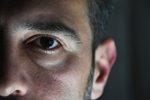 Portrait of young adult man. Man eye. Close-up on eye with copy space