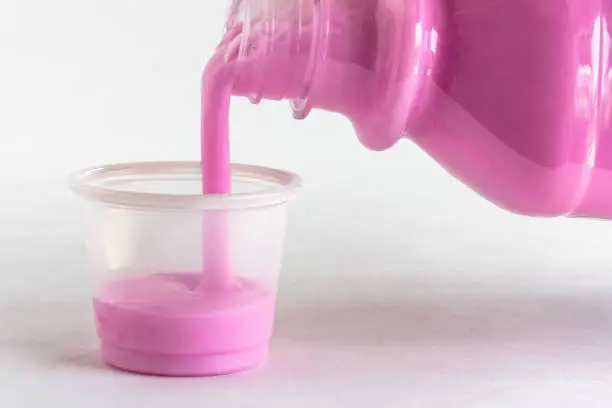 Pouring Pink Bismuth into a Dose Cup