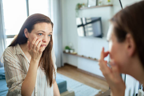 istock Young woman putting on makeup while looking in a mirror at home 1503455386