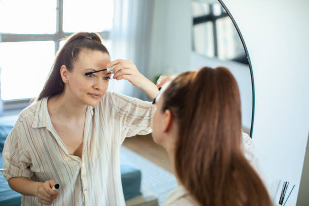 istock Young woman putting on makeup while looking in a mirror at home 1503456686