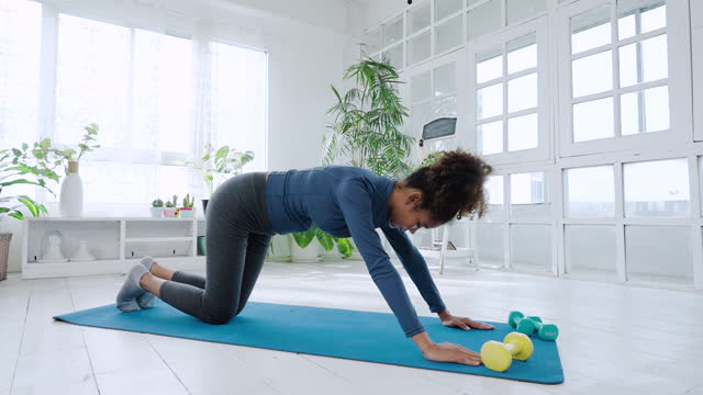Young black pregnant woman exercising at home