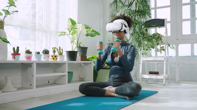 Young black pregnant woman wearing virtual reality glasses exercising at home
