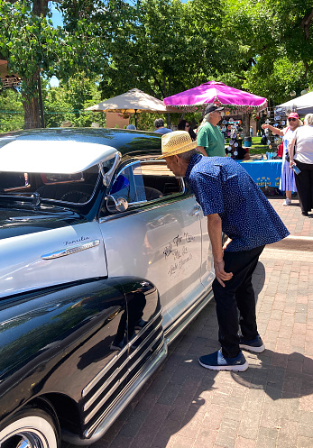 Santa Fe, NM: A senior man bends over to admire the interior of a 1948 Chevy lowrider car on the historic Santa Fe Plaza on the annual (June) Lowrider Day.