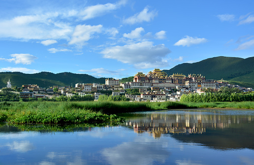 Songzanlin Tibetan Buddhist Monastery reflecting in the water of the sacred lake in Shangri-La, Yunnan province, China