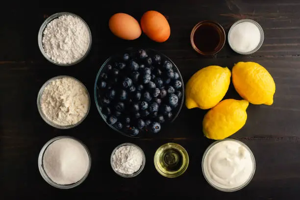 Fresh blueberries, lemons, and other raw ingredients on a rustic wooden background