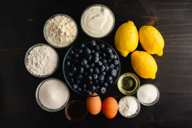 Fresh blueberries, lemons, and other raw ingredients on a rustic wooden background