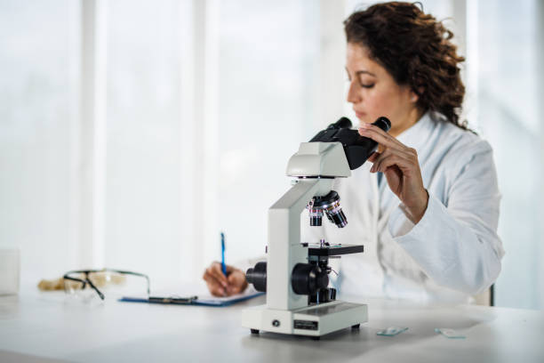 istock Female scientist writing the results of analyzed samples after examining them under a microscope 1503533922