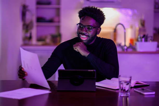 istock A multicultural digital assistant is sitting at home late at night in a purple lighted room and having a video call with a manager. 1503534295