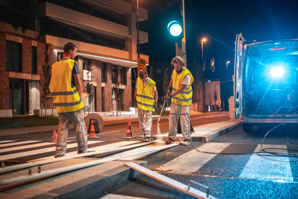 Spray Painting A Crosswalk With A Spray Gun Construction worker wearing a reflective vest spray painting a crosswalk with a new layer of white paint using a spray gun. freshly painted road markings stock pictures, royalty-free photos & images