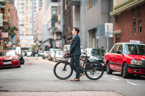 young chinese male employee crossing the street with a bicycle - 2322 imagens e fotografias de stock