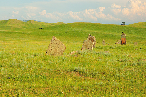 A group of ancient stone burial stones in a hilly steppe under a clear summer sky. Khakassia, Siberia, Russia.
