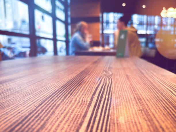 Person wearing a black suit, white laptop, and yellow coffee mug on a wooden table