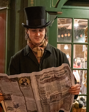 San Francisco, CA. Gentleman reading a newspaper at the Dickens Fair, Cow Place, Daly City. The festival happens annually around Christmas.
