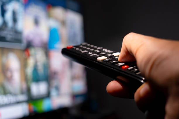 istock His hand was holding a remote control. Multimedia TV broadcasting online for entertainment to watch at his home. Background Broadcast concept. 1503701996
