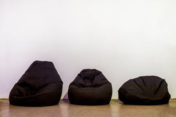 three frameless dark armchairs near a light wall. Modern mockup design