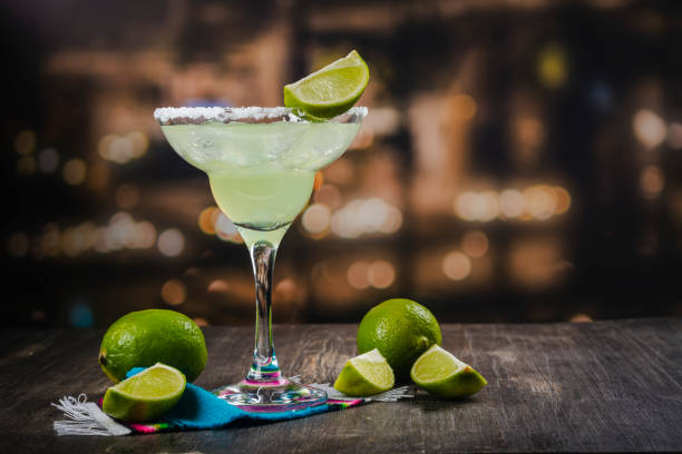 Margarita cocktail with lime Margarita cocktail with sliced and whole limes on wooden bar table. Mexican party background margarita stock pictures, royalty-free photos & images