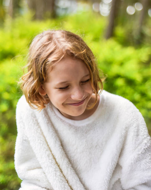 portrait of shy 10 years old blond curly girl smiling and hiding - 10 11 years child human face female imagens e fotografias de stock